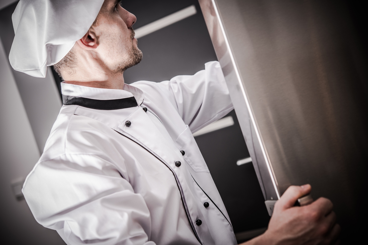 Chef trabajando en una cocina equipada con mobiliario de acero inoxidable.