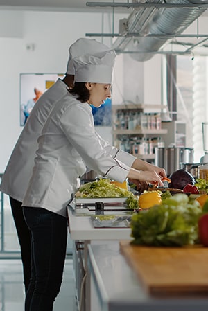 Chef trabajando en una cocina equipada con mobiliario de acero inoxidable.